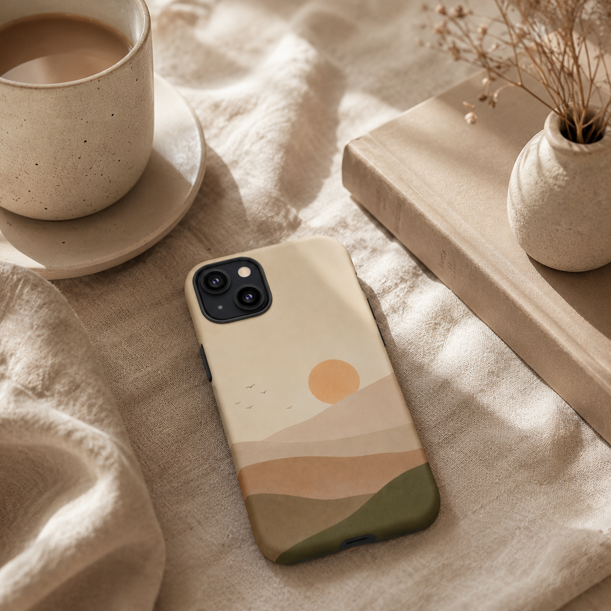 Phone case with a landscape design on a textured surface with a cup and plant.
