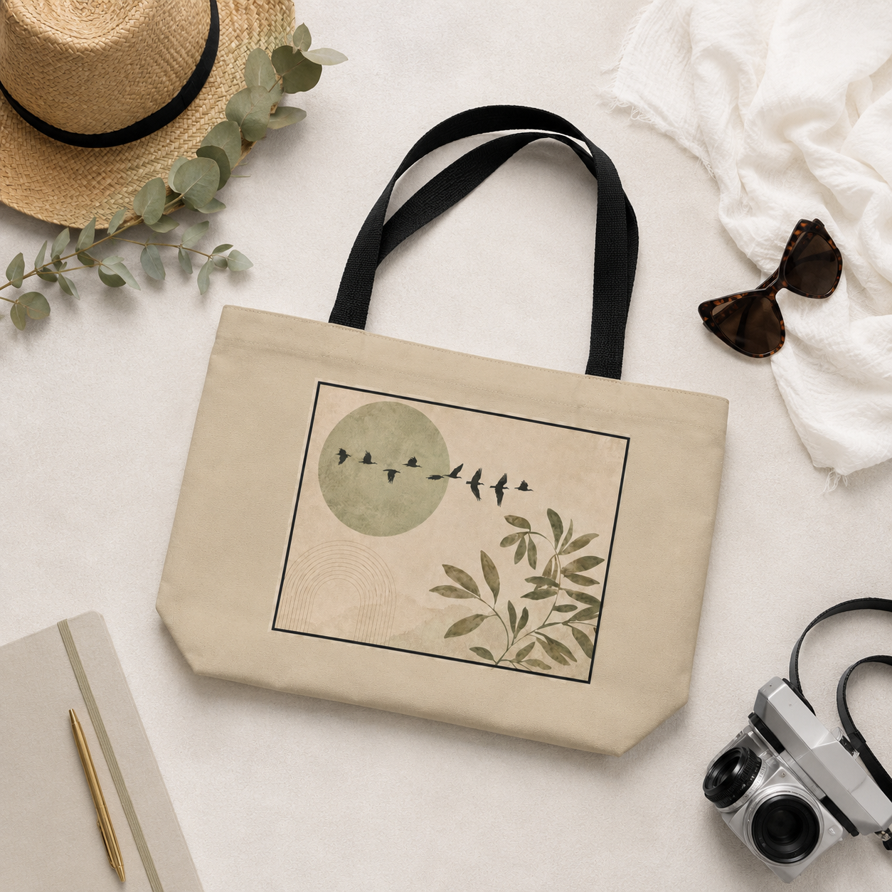 Beige tote bag with nature-themed design on a light surface with accessories.