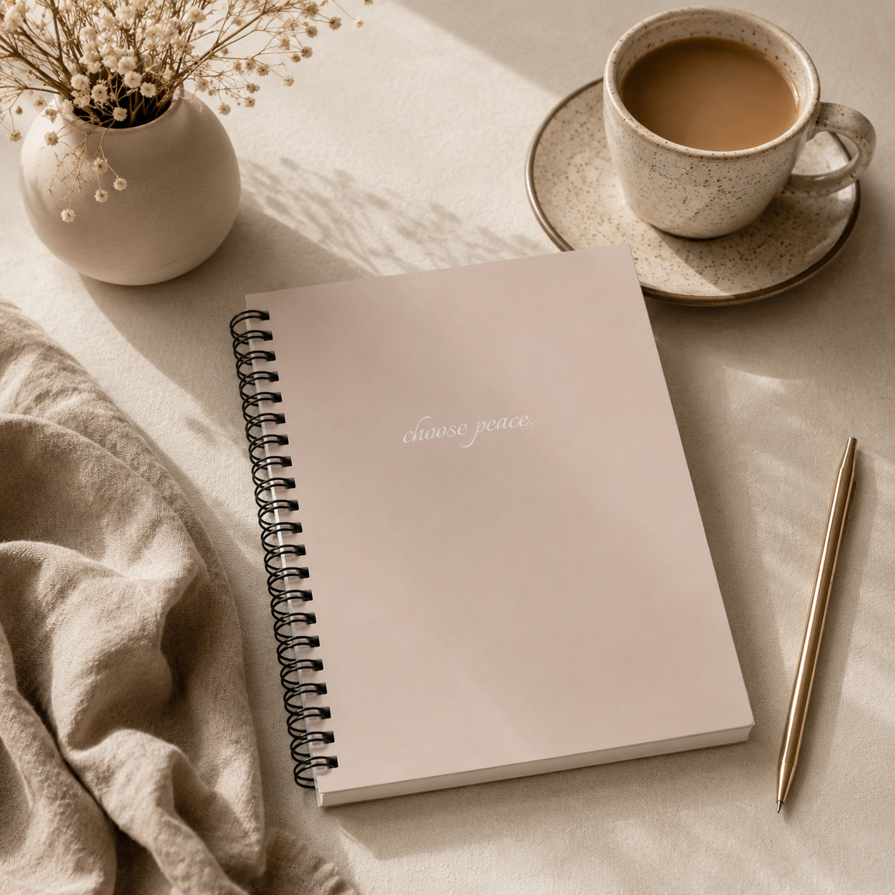 Notebook with 'Choose peace' text, cup of coffee, and pen on a light surface