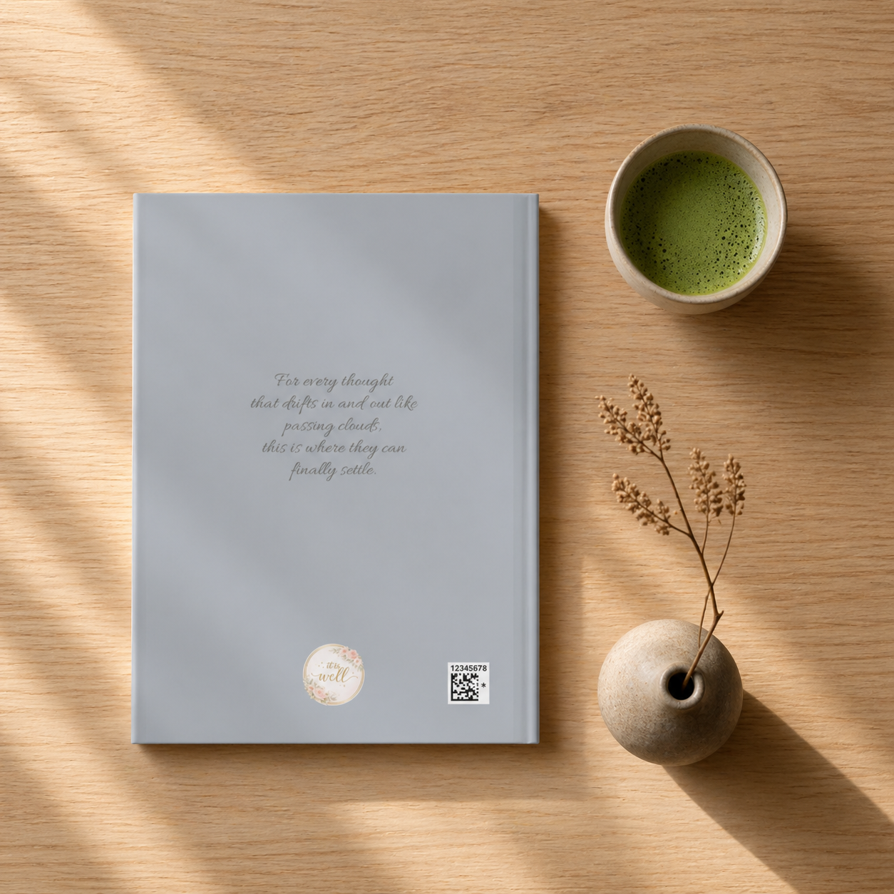 Notebook with a cup of green tea and a small vase on a wooden surface