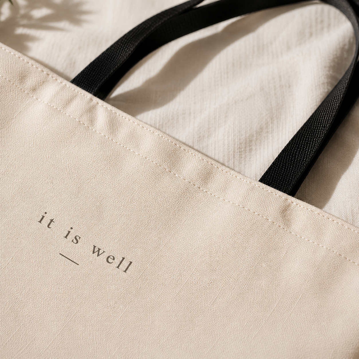 Beige tote bag with 'it is well' text on a neutral background