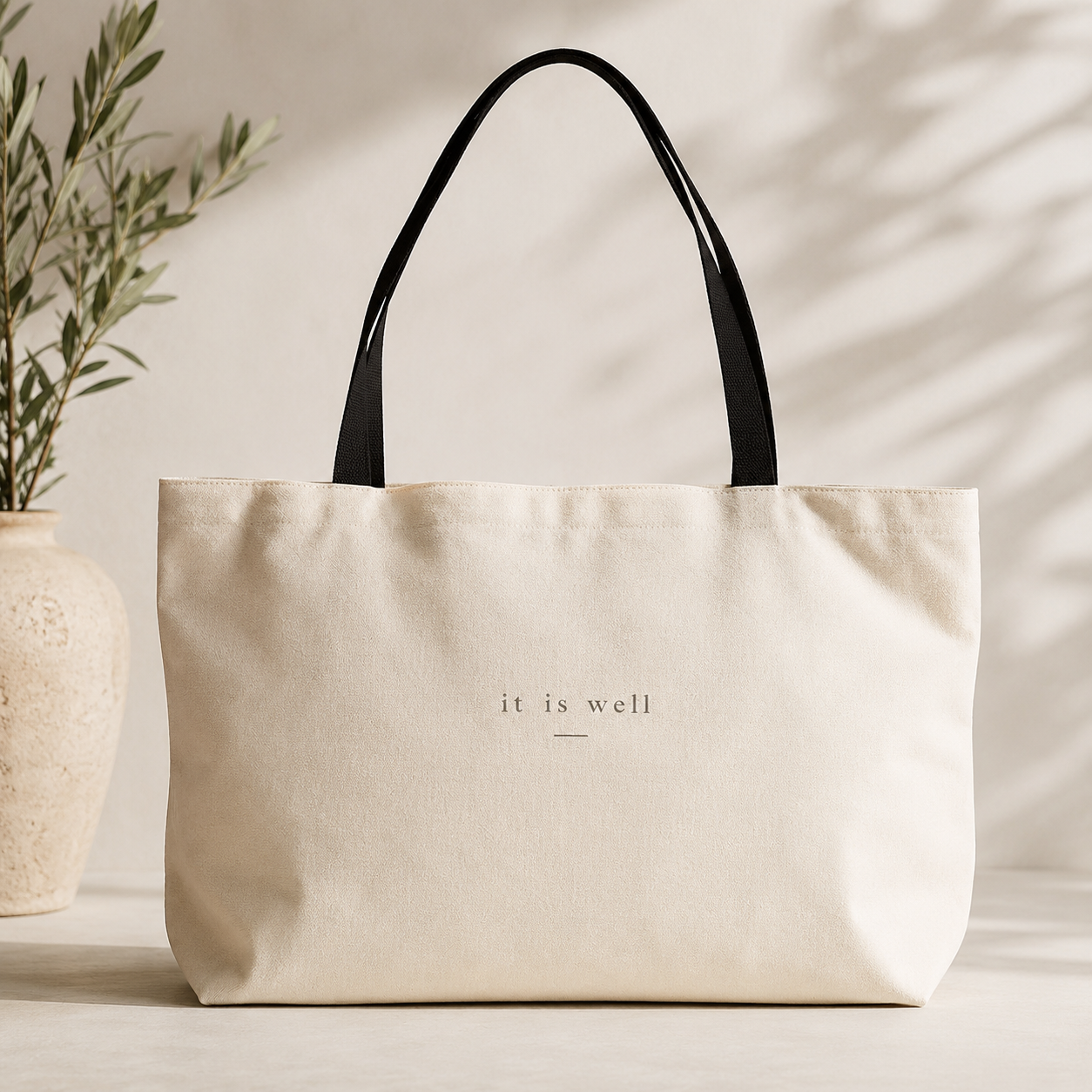Beige tote bag with 'it is well' text on a light background